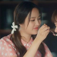 a young woman is brushing her teeth with a spoon