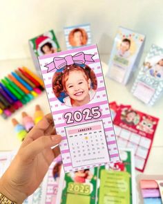 a person holding up a pink and white calendar with pictures of children's faces on it