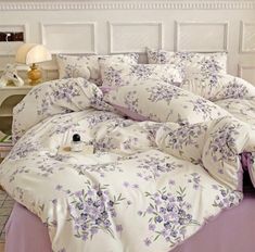 a bed with purple and white flowers on the comforter is shown in this image