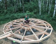 a man sitting on top of a wooden structure in the woods