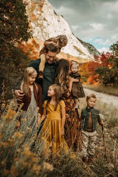 a group of people that are standing in the grass with some trees and mountains behind them