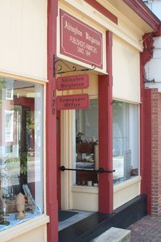 the storefront of an antique furniture shop with red trim and signs on it's windows