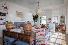 a living room filled with lots of furniture next to a table and lamps on top of it