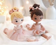 two crocheted dolls sitting on top of a white bed next to each other