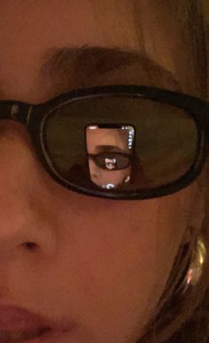 a close up of a person wearing glasses and holding a cell phone to their face