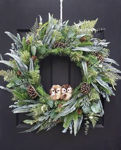 a wreath with pine cones, evergreen leaves and two little owls on the front door