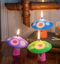 two colorful candles sitting on top of a wooden table