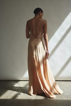 the back of a woman's dress as she stands in front of a white wall