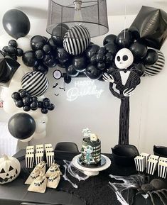 a birthday party with black and white decorations, balloons, and skeleton cake toppers