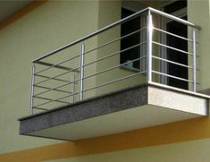 a balcony with railings and windows on the side of a yellow building in front of a window