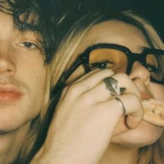 a man and woman are looking at something with glasses on their faces as they eat food