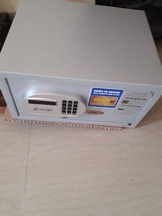 a microwave sitting on top of a counter next to a remote control box with the door open