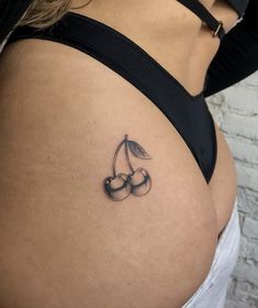 a woman's stomach with two cherries tattoo on her left side ribcage