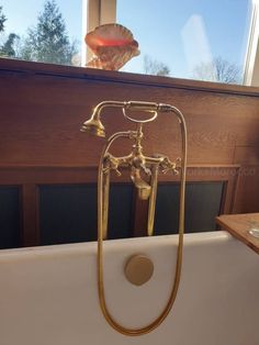 a bathtub with a gold faucet and shower head in front of a window