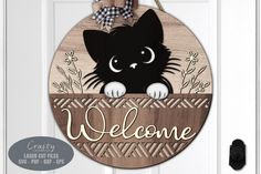 a door hanger with a black cat peeking out from behind a welcome sign that reads,'welcome '