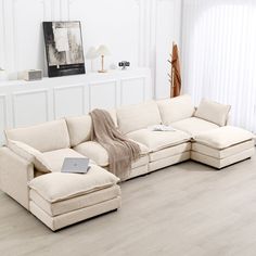 a living room with white walls and wooden floors has a large sectional sofa set on the floor