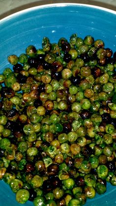 a blue bowl filled with green and black olives