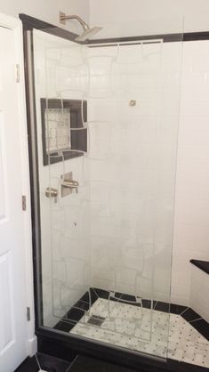 a walk in shower sitting inside of a bathroom next to a white door and black counter top