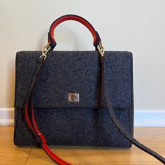 Elevate Your Accessory Game With This Hugo Boss Runway Edition Handbag, Meticulously Crafted In Italy. This Sophisticated Handbag Features A Structured Silhouette In Dark Grey Felted Wool, Contrasted By Striking Orange Leather Interior And Gold Tone Accents. The Gold-Tone Hardware, Including The Elegant Turn-Lock Closure, Adds A Touch Of Luxury, While The Adjustable Shoulder Strap Allows For Versatility In Stylingwhether You Prefer To Carry It By Hand Or Wear It Crossbody For Hands-Free Ease. A Hugo Boss Wallet, Boss Runway, Laptop Handbag, Office Bag, Orange Leather, Runway Collection, Felted Wool, Work Travel, Leather Interior