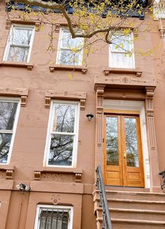 an apartment building with stairs leading up to the front door and two windows on each side