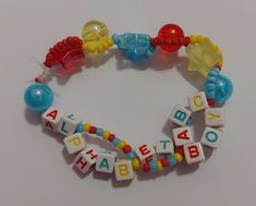 a close up of a bracelet made out of letters and beads on a white surface