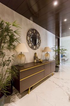 a living room with two lamps and a large mirror on the wall next to a plant