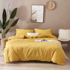 a bed with yellow sheets and pillows in a room next to a clock on the wall