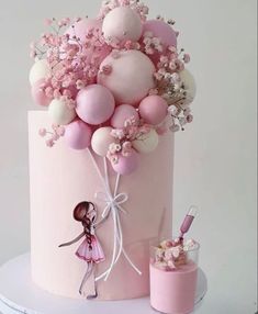 there is a pink cake with balloons on it