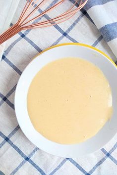 a white bowl filled with batter on top of a blue and white checkered table cloth