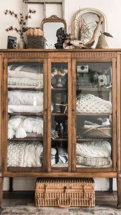 a wooden cabinet with glass doors and baskets on top