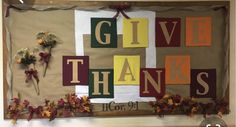 a bulletin board with the words give thanks written on it and flowers in front of it