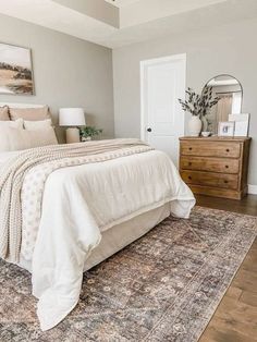 a bed sitting on top of a wooden floor next to a dresser and mirror in a bedroom