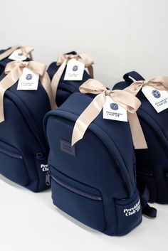 three blue backpacks with bows tied around them