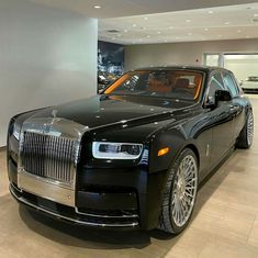 a black rolls royce parked in a showroom