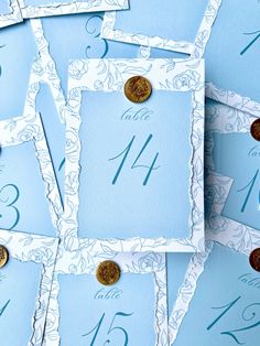 blue and white wedding table numbers with gold buttons on each card, surrounded by other cards