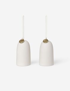 two white bell ornaments with gold accents on each one and a string hanging from the top