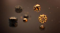 an array of shiny objects floating on top of a black surface with water droplets around them