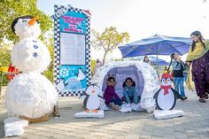 children are playing in an igloose with snowmen and penguins on the sidewalk