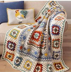 a couch with a crocheted blanket on top of it next to a pillow