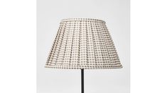 a lamp that is sitting on top of a metal stand with a white and brown checkered lampshade