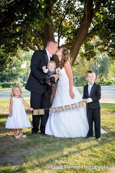 a bride and groom kissing with their children