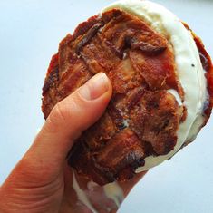 a person is holding up an ice cream covered doughnut with bacon on it's side