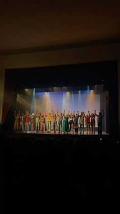 a group of people standing on top of a stage with their arms in the air