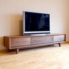 a flat screen tv sitting on top of a wooden entertainment center next to a window