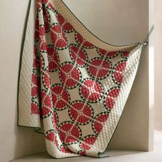 a red and white quilt hanging from the side of a wall