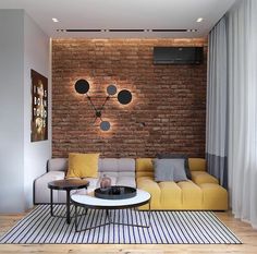 a living room with brick wall and yellow couch in the center, coffee table on striped rug