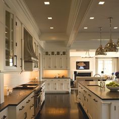 a large kitchen with white cabinets and black counter tops, along with an island in the middle