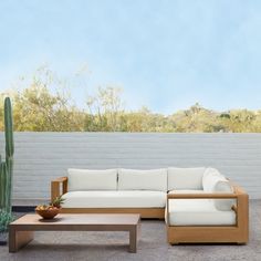 a white couch sitting next to a wooden coffee table on top of a cement floor