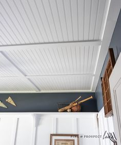 the ceiling is painted blue and has white paneling on it, along with an old framed photograph