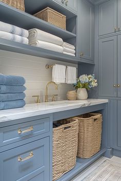 a bathroom with blue cabinets and towels on the counter top, along with two wicker baskets filled with flowers